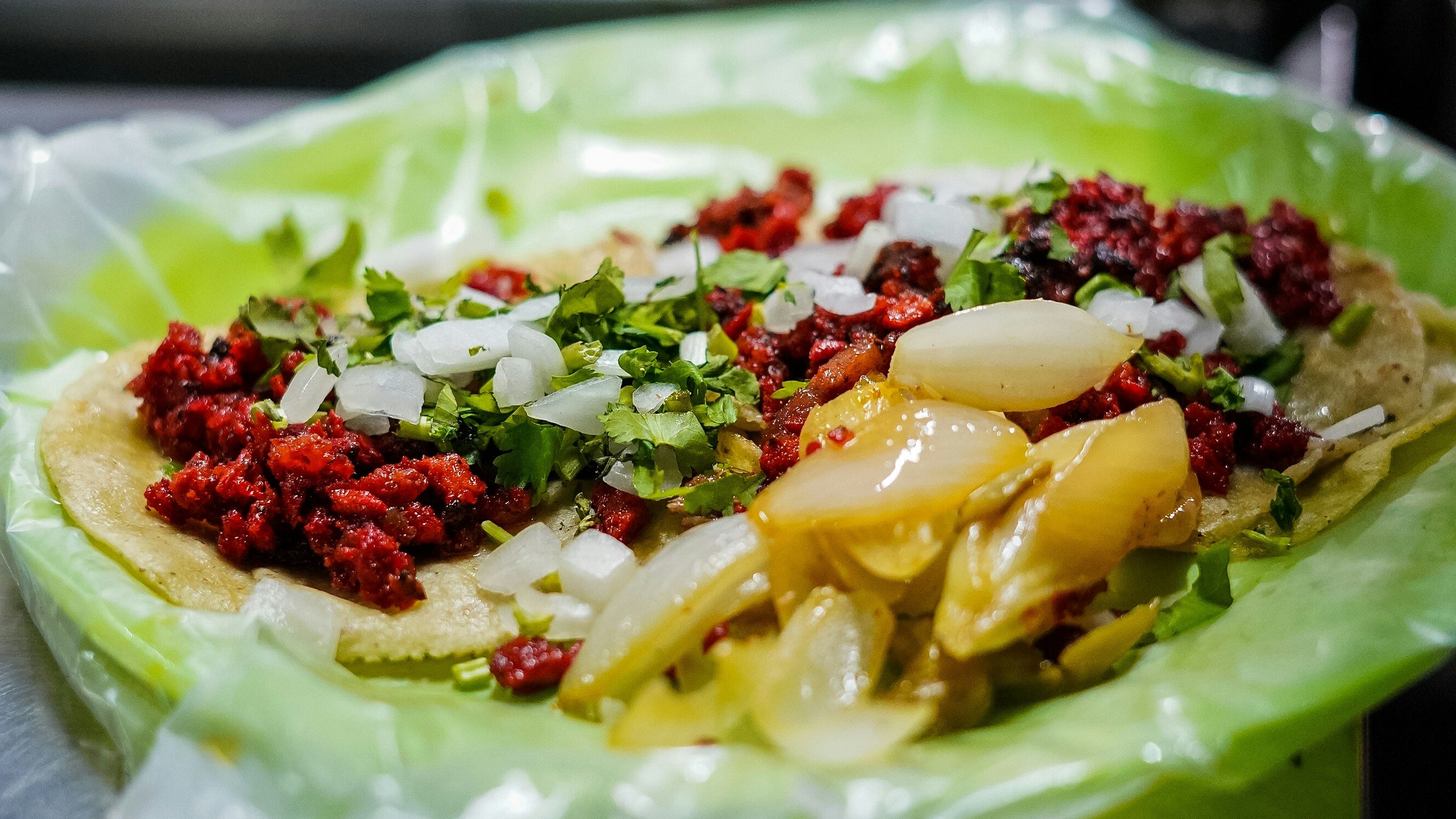 Close-up of authentic street food tacos served on corn tortillas, topped with fresh cilantro and onions in Mexico.