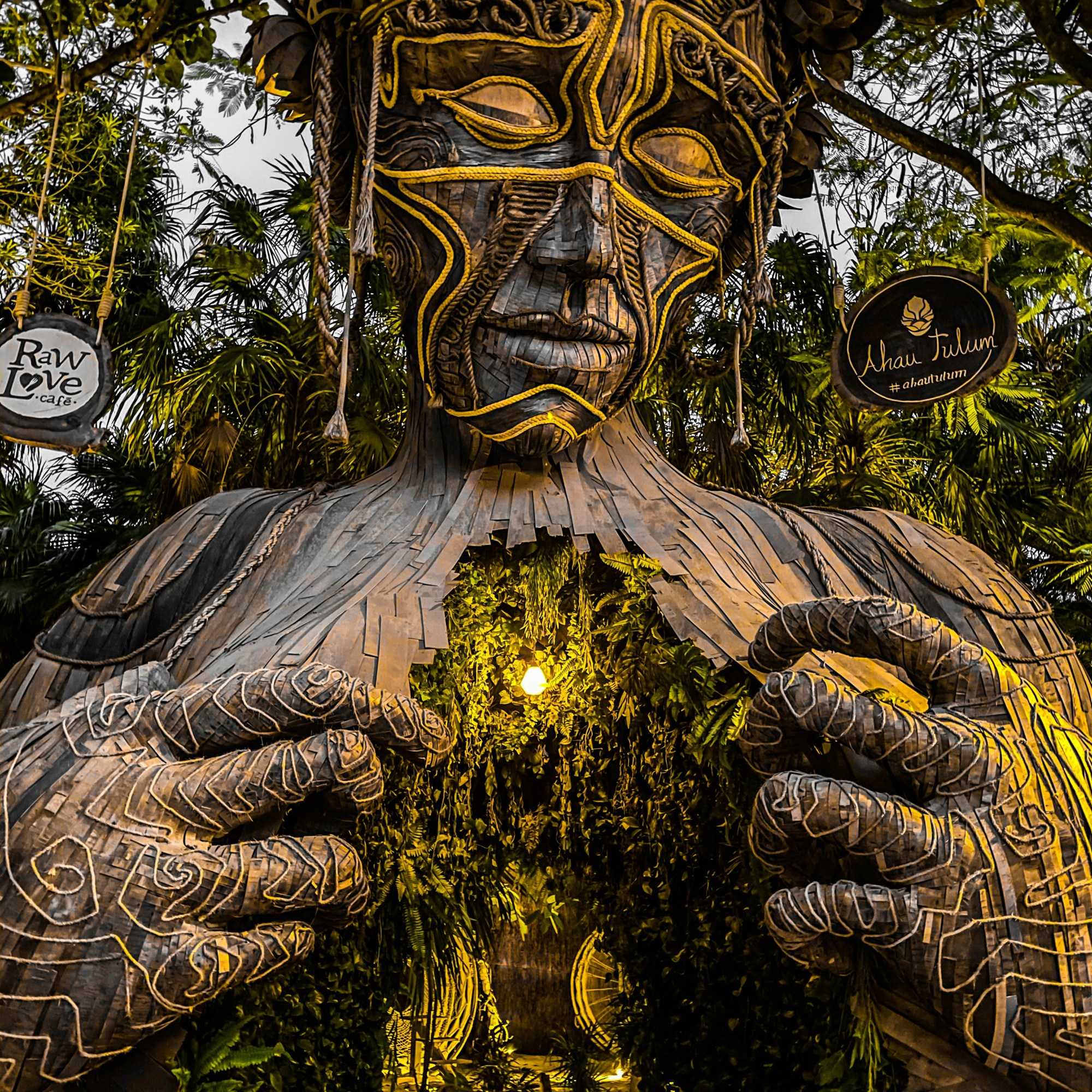 Ven a la Luz sculpture in Tulum surrounded by trees with glowing light in the center.