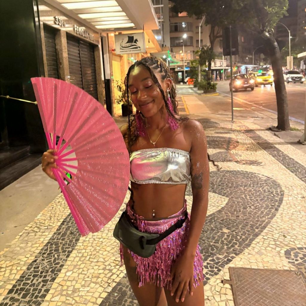 Woman in a glittery carnival outfit standing on a street in Copacabana, Rio de Janeiro at night.